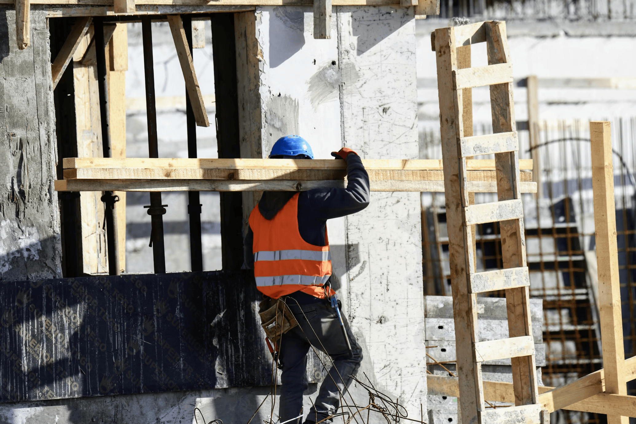 Images of construction workers wearing hard hats and safety vests at a work site