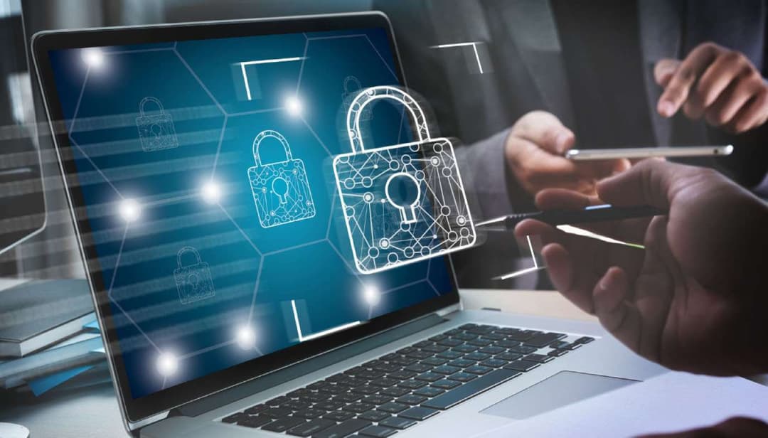 Image of a person sitting at a couch, with a laptop on their lap, working on cyber security